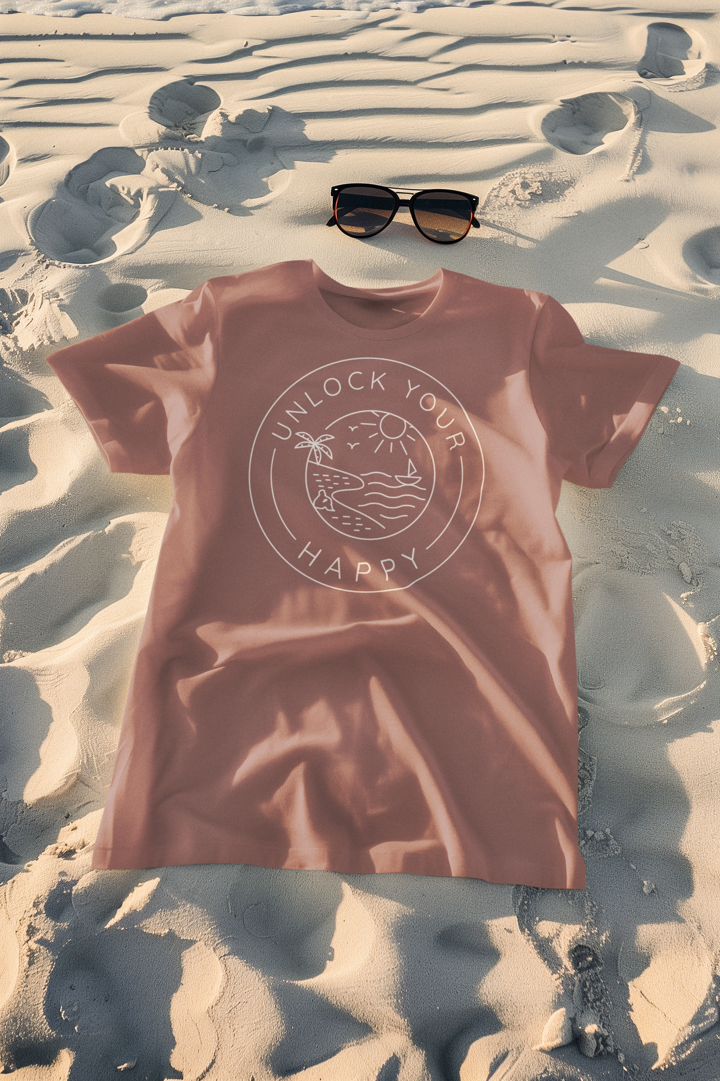 A beach scene with an outline of a figure sitting on the sand under a palm tree, looking out at a boat with the text 'Unlock Your Happy' on a nature-themed t-shirt.