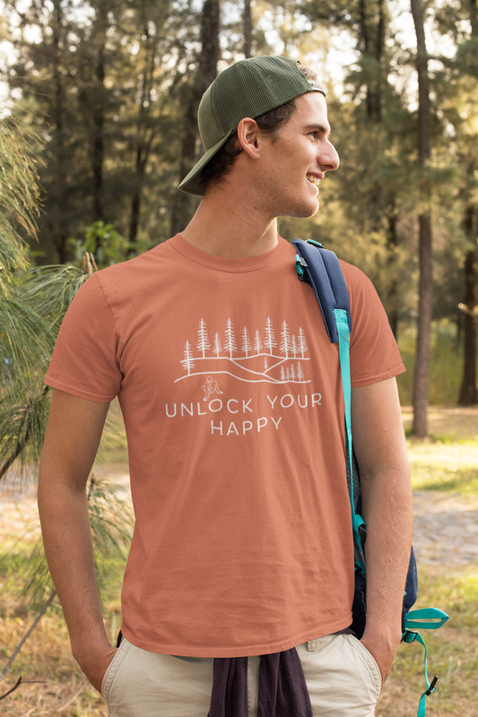 Graphic of a t-shirt depicting a tranquil woods scene with tall trees. A figure is shown taking in the peaceful surroundings. The text 'Unlock Your Happy' is displayed.